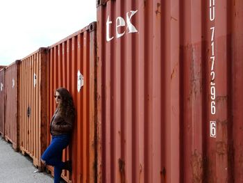 Portrait of young woman standing against brick wall