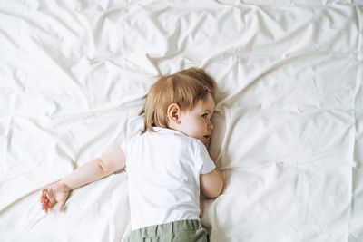 Cute funny baby girl in home clothes lies on bed at home