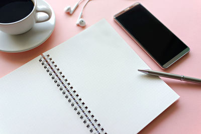 Directly above shot of coffee by diary and pen on table