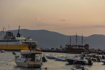 Boats moored at harbor against sky during sunset