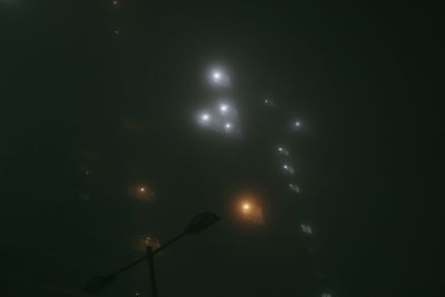 Low angle view of illuminated street lights against sky at night