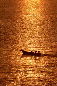 Silhouette of two people in a boat at sunset