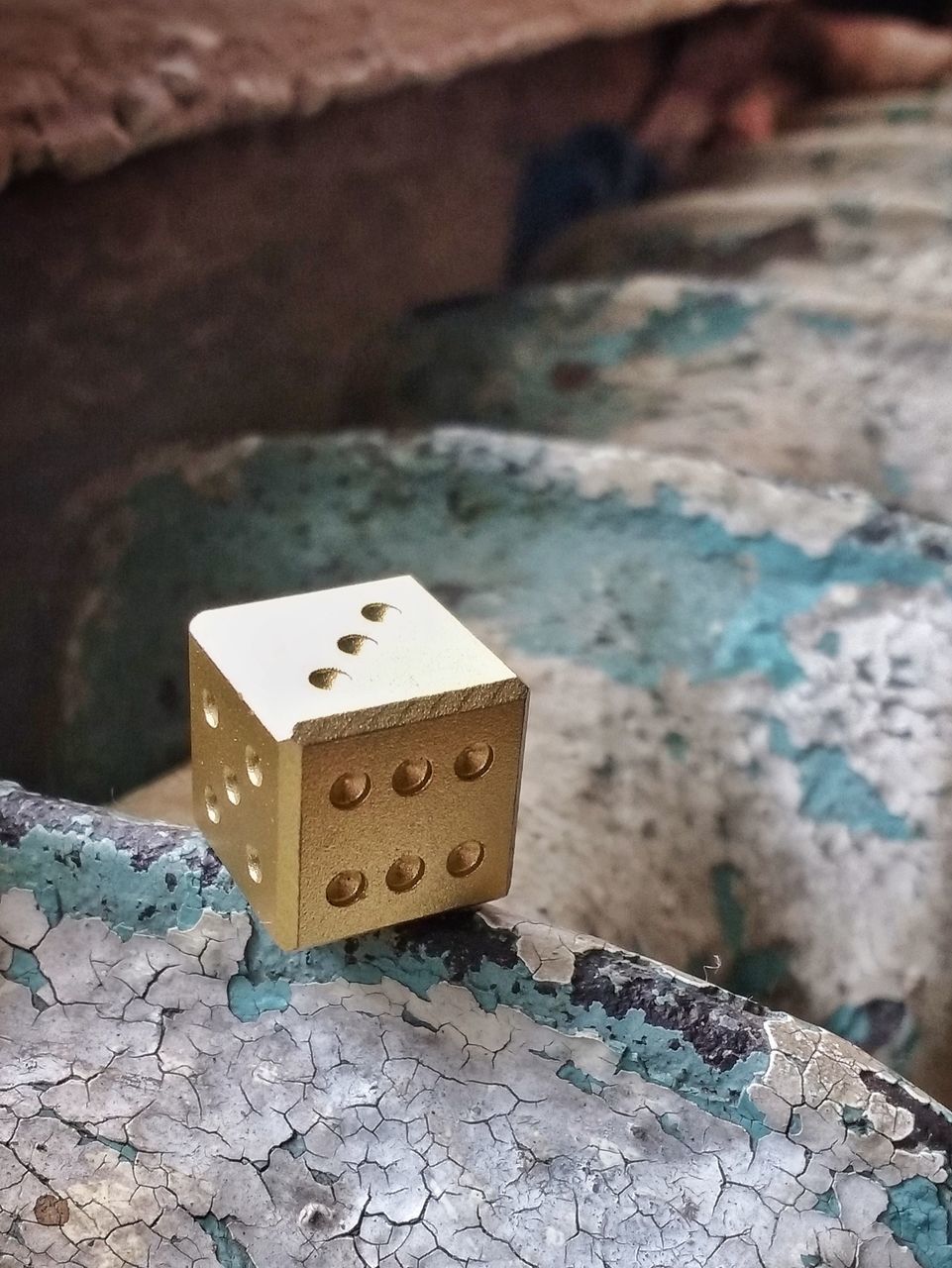 focus on foreground, no people, close-up, textured, still life, high angle view, day, solid, rough, pattern, outdoors, wall, number, rock, toy, dice, old, single object, selective focus