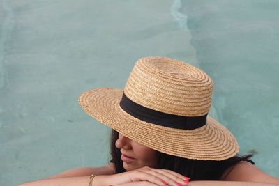 Midsection of woman relaxing in swimming pool against sea