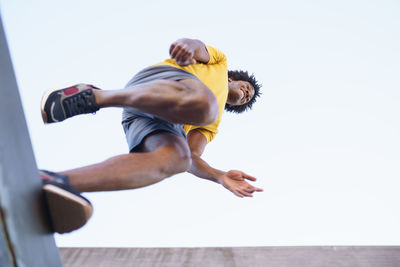 Low angle view of man exercising against sky