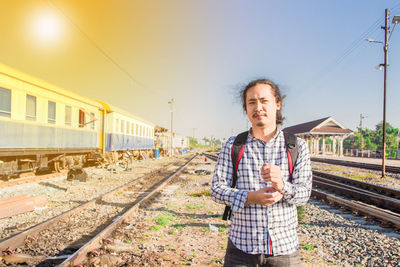 Portrait of man standing on railroad tracks against sky