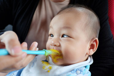 Midsection of mother feeding baby boy