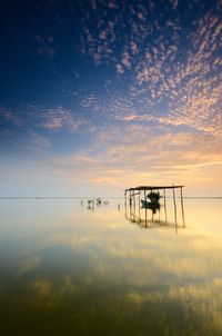 Silhouette boat on lake against sky during sunset