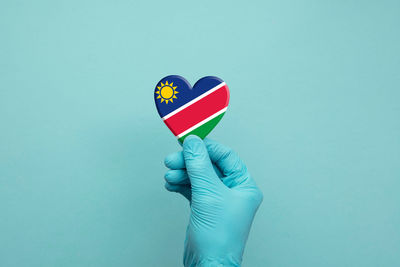 Close-up of hand holding flag against blue background