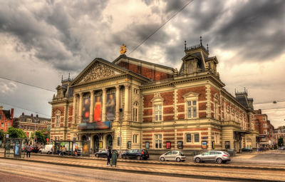 Cars on street by buildings against sky in city