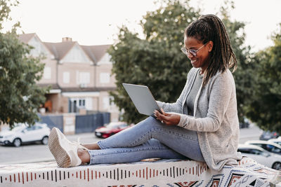 Happy woman using laptop on terrace at sunset