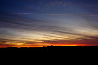 Silhouette landscape against dramatic sky during sunset