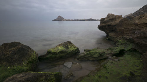 Rocks by sea against sky