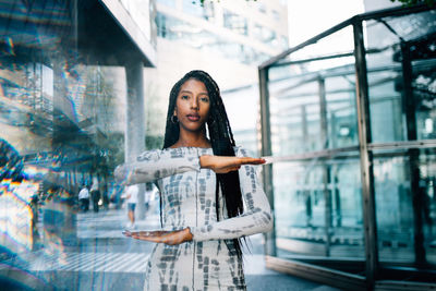 Young woman looking away while standing on glass window