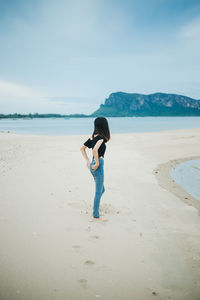 Woman standing on beach against sky