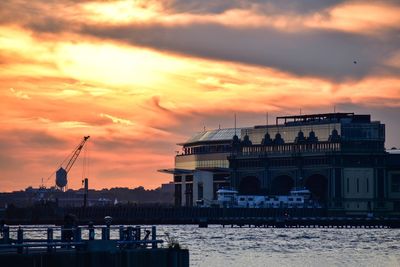 Buildings by sea against sky during sunset