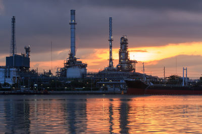 Illuminated factory against sky during sunset