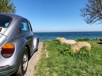 Scenic view of sea against clear blue sky and a vw beetle