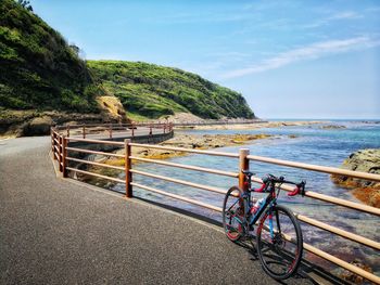 Bicycle by sea against sky