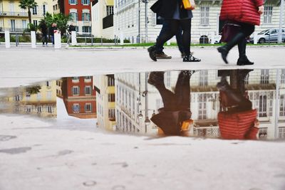 Low section of people walking on street in city