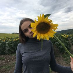 Midsection of woman holding sunflower against sky