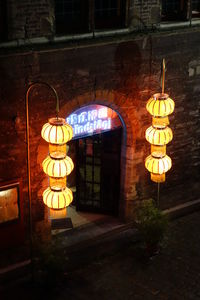 Illuminated lanterns hanging on wall by street at night