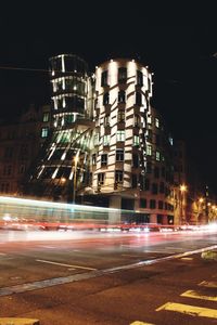 Light trails on street against illuminated buildings at night