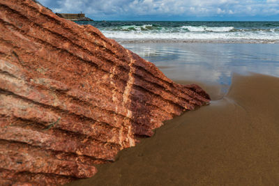 Scenic view of pink granite rock on beach against sea and sky