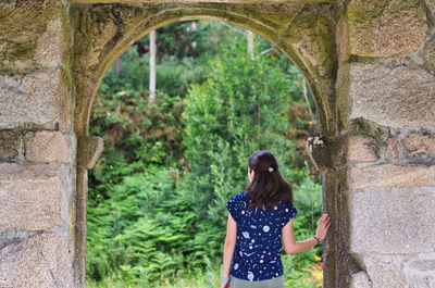 Girl going into nature trough a big stone portal