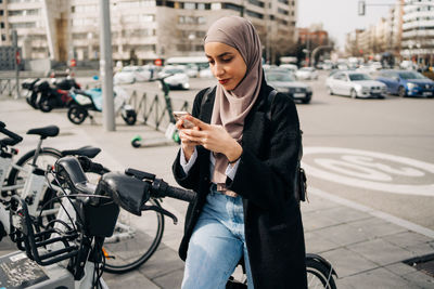 Young woman riding bicycle on road in city