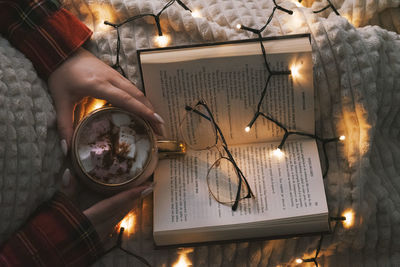 Christmas decorations with lights, hot drink, fruits and a good book