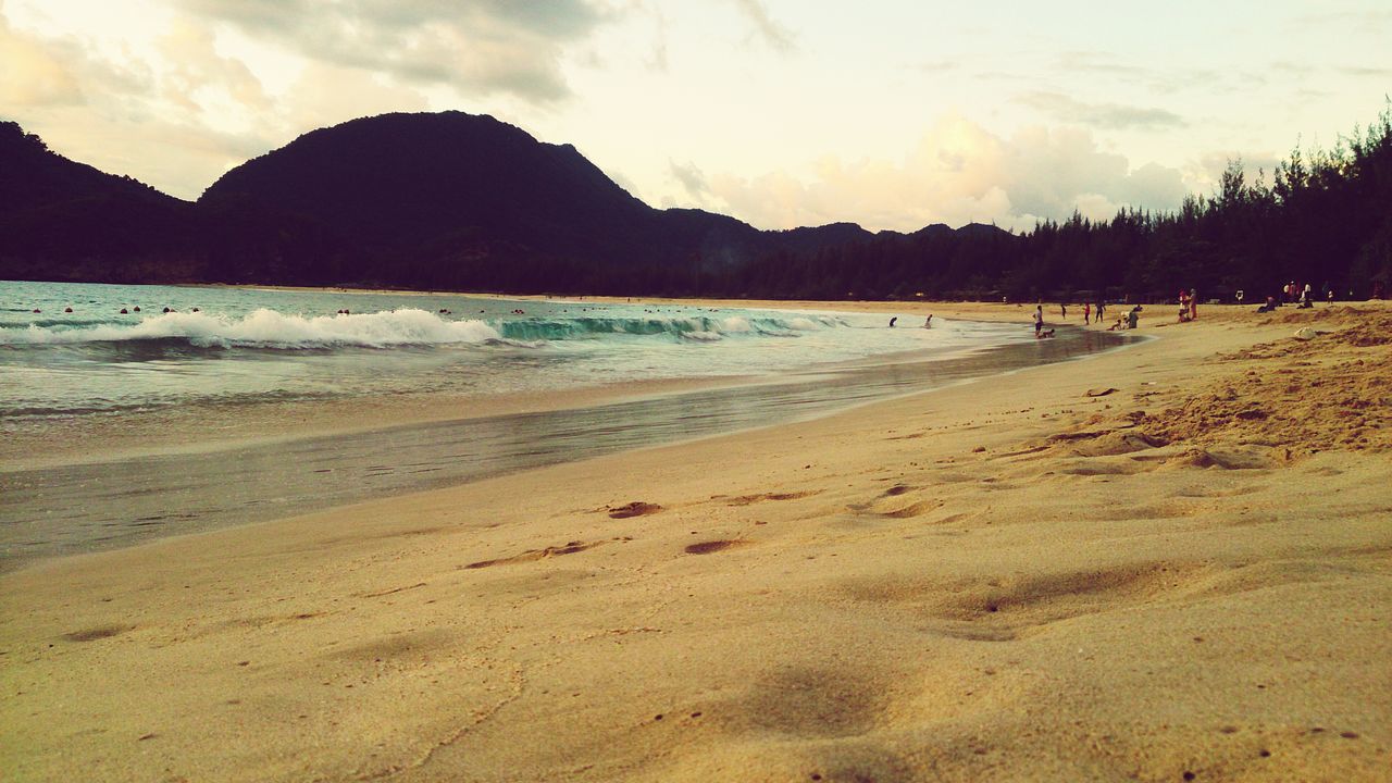 beach, sand, water, sea, shore, scenics, sky, tranquil scene, tranquility, beauty in nature, mountain, nature, coastline, incidental people, idyllic, wave, vacations, tourism, cloud - sky, sunlight