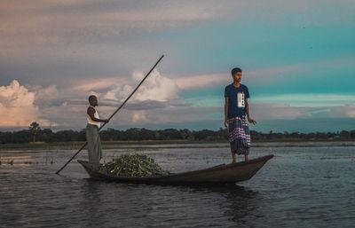 Man standing on boat in sea against sky