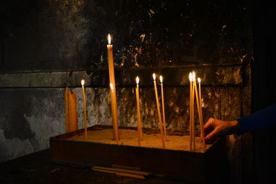 Close-up of hand holding lit candles in temple