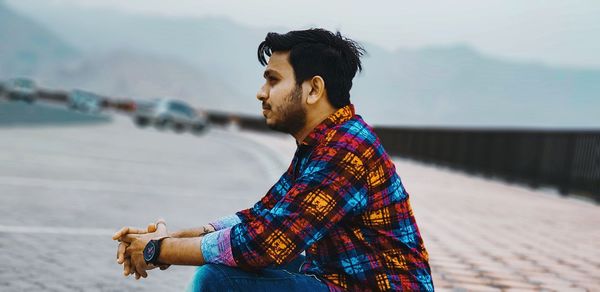 Side view of young man looking away at beach