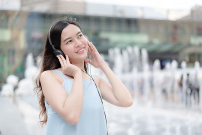 Beautiful young woman using phone while standing outdoors