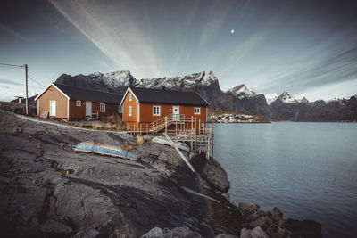 Houses by sea and buildings against sky