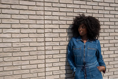 Young woman standing against brick wall