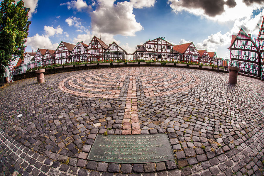 architecture, built structure, sky, building exterior, cloud - sky, cobblestone, cloud, cloudy, city, paving stone, day, pattern, outdoors, footpath, the way forward, sunlight, walkway, street, diminishing perspective, incidental people