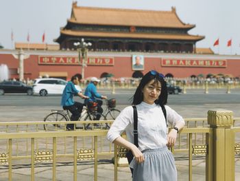 Full length portrait of young woman standing in city