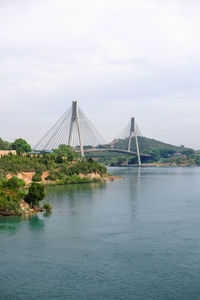 Suspension bridge over river against sky