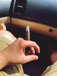 Close-up of hand holding cigarette in car