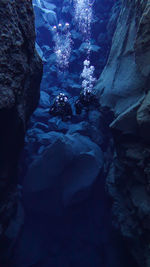 Scuba divers swimming in underwater cave
