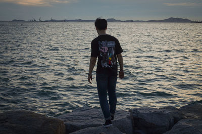 Rear view of man standing on beach against sky
