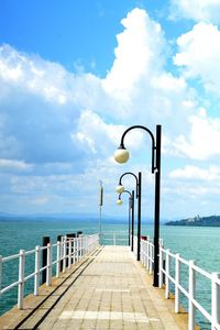 Pier on sea against cloudy sky