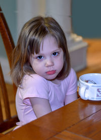 Small girl sits at a table not eating her food. a picky eater