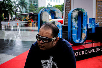 Mid adult man wearing sunglasses while sitting outdoors