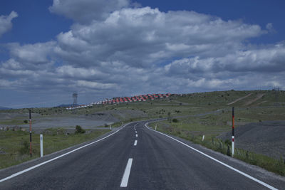 Empty road by landscape against sky