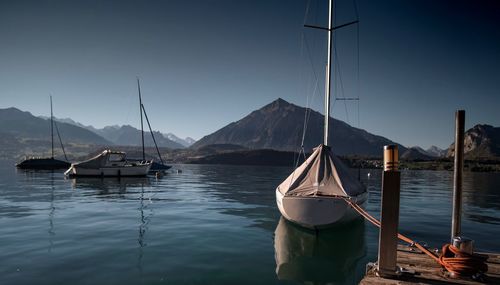 Sailboats moored in lake against sky