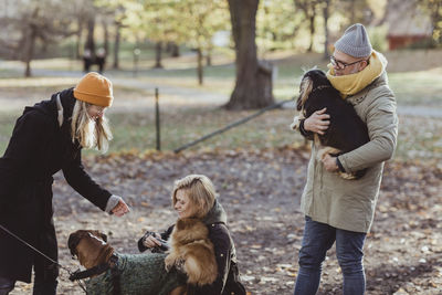 Smiling women and man playing with dogs at park